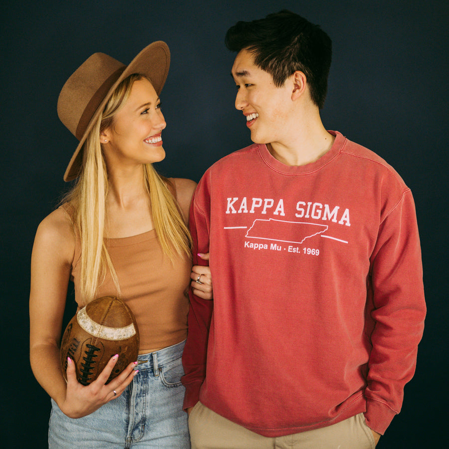 Boy and girl stand arm in arm. Boy wears red sweatshirt with Kappa Sigma written across it.